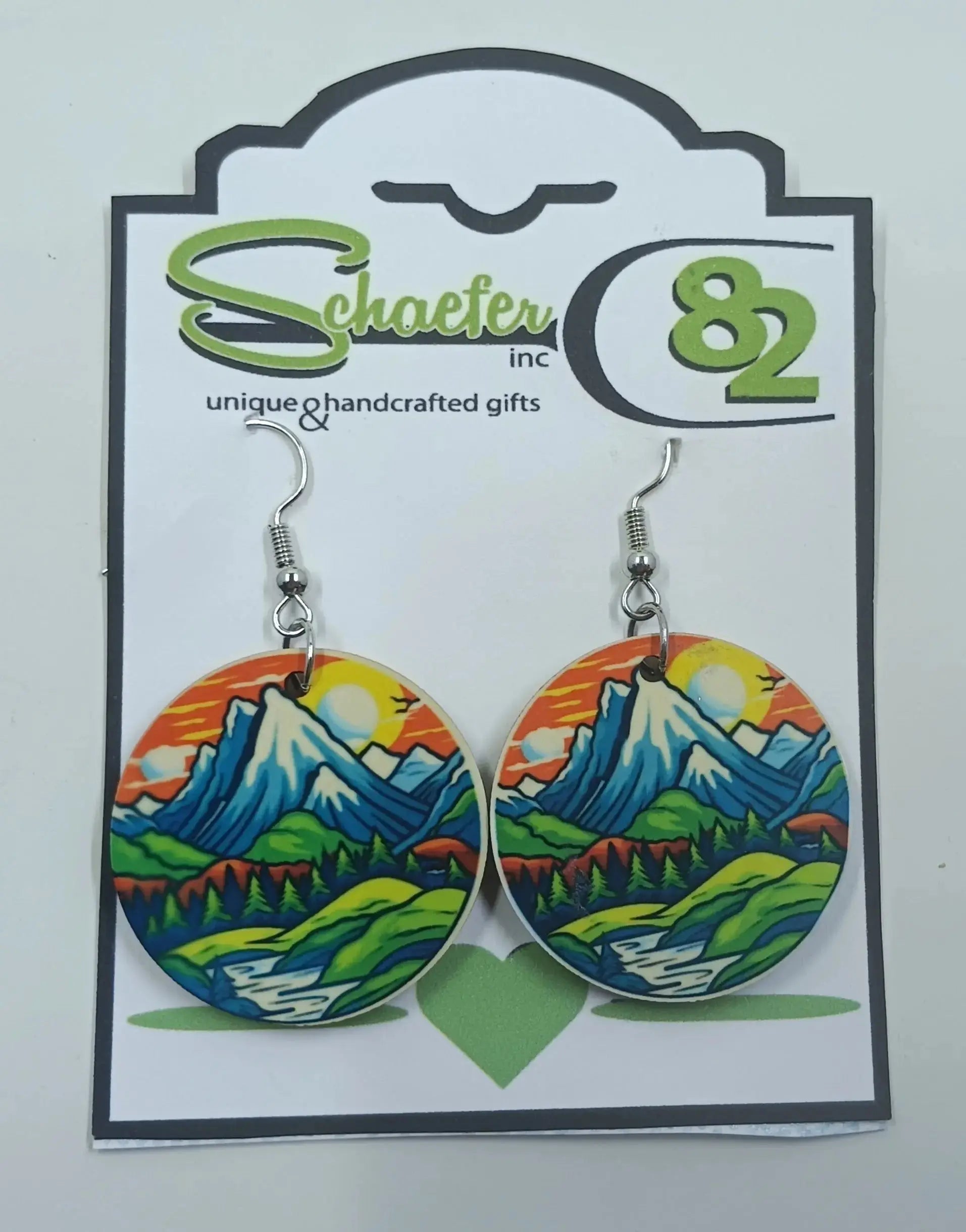 Colorful mountain earrings that has an orange sunset and river with green valleys