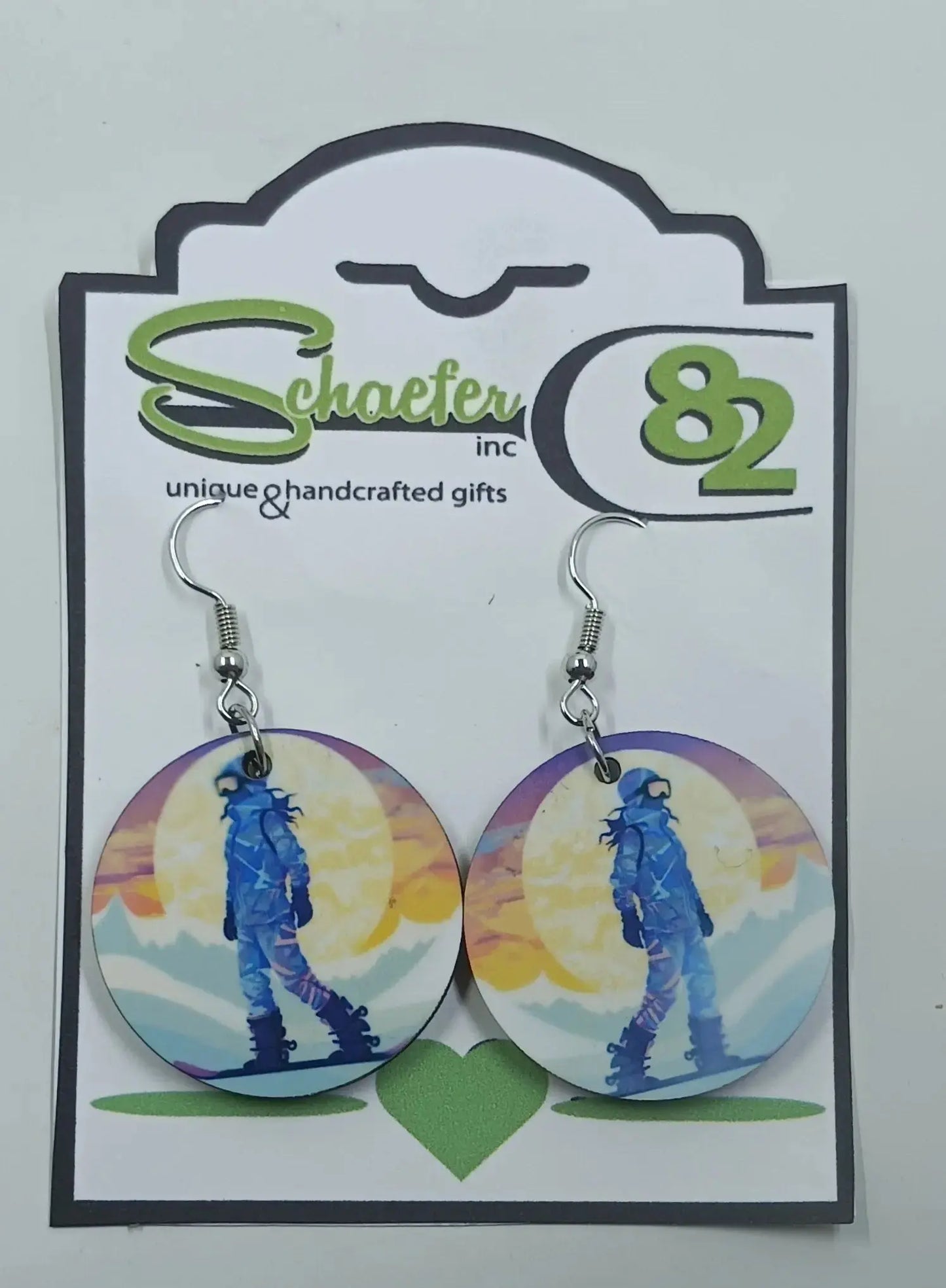 These gorgeous snowboarding earrings are made using sublimation  techniques. there is a snowboarder, in front of a huge sun, and is snowboarding down the mountain
