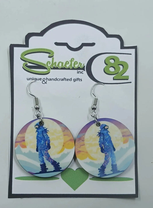 These gorgeous snowboarding earrings are made using sublimation  techniques. there is a snowboarder, in front of a huge sun, and is snowboarding down the mountain
